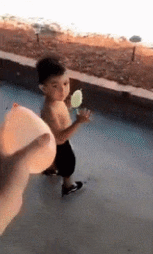 A Little Boy Is Holding An Ice Cream Cone In His Hand While Walking Down The Street . GIF