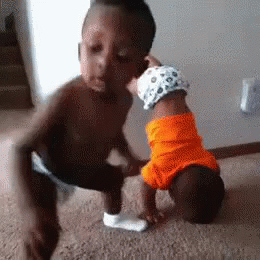 A Little Boy Is Kissing A Baby On The Cheek . GIF