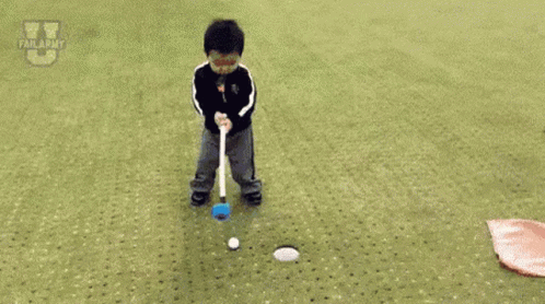 A Little Boy Is Laying On The Ground Near A Hole In The Grass . GIF