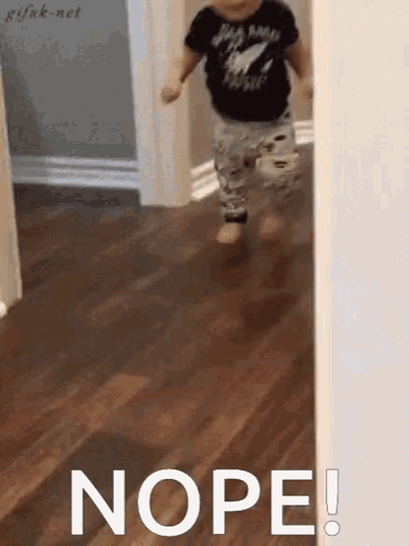 A Little Boy Is Running Through A Hallway And The Word Nope Is Written On The Floor . GIF