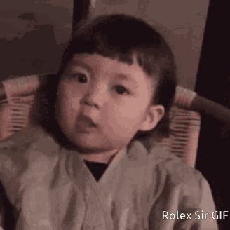A Little Boy Is Sitting In A Chair And Making A Face . GIF