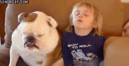 A Little Boy Is Sitting On A Couch With A Bulldog . GIF