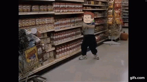A Little Boy Is Standing In A Grocery Store Holding A Bottle Of Tomato Sauce . GIF