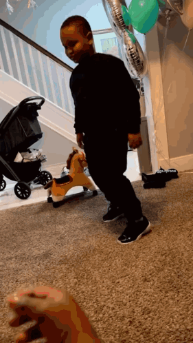 A Little Boy Is Standing In Front Of A Rocking Horse And Balloons That Say ' Daddy ' On Them GIF