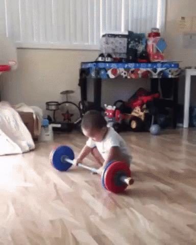 A Little Boy Playing With A Barbell On The Floor GIF