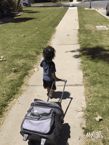 A Little Boy Pulling A Suitcase Down A Sidewalk With The Words Motion Girls Written On The Bottom GIF