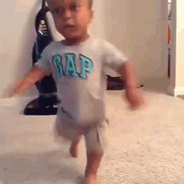A Little Boy Wearing A Gap Shirt Is Running On The Floor . GIF