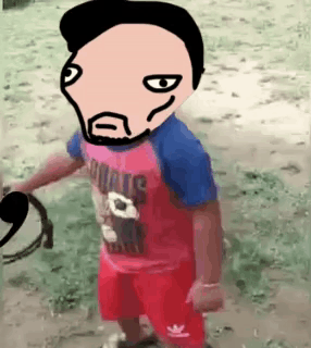 A Little Boy Wearing A Red And Blue Shirt And Red Shorts Is Standing In The Dirt With A Cartoon Face On His Head . GIF
