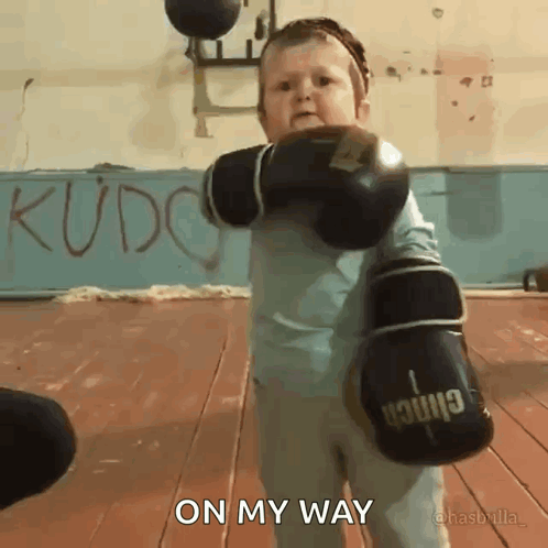 A Little Boy Wearing Boxing Gloves With The Words On My Way Above Him GIF