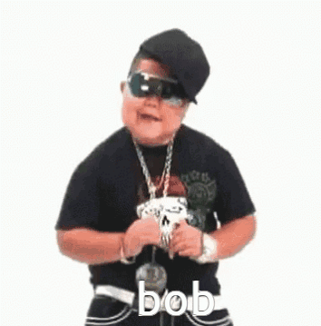 A Little Boy Wearing Sunglasses , A Hat , A Necklace And A Skull Necklace Is Dancing . GIF