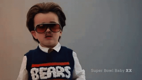 A Little Boy Wearing Sunglasses And A Sweater That Says Nerds On It GIF