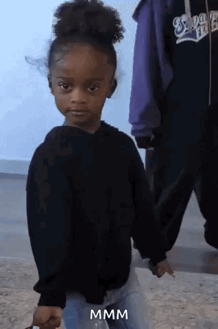 A Little Girl In A Black Sweater Is Holding Someone 'S Hand And Making A Funny Face .. GIF
