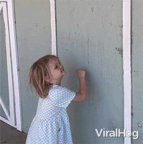 a little girl in a blue and yellow dress is standing in front of a wall .