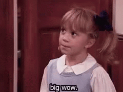 A Little Girl In A Blue Dress Is Standing In Front Of A Door . GIF