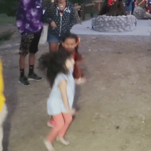 A Little Girl In A Blue Shirt And Pink Pants Is Dancing In The Dirt GIF