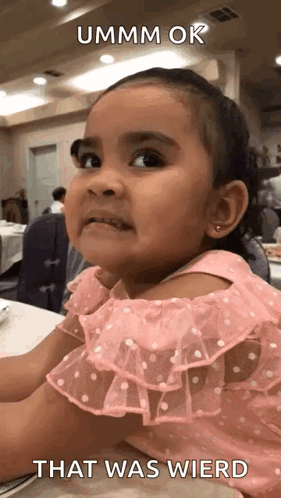 A Little Girl In A Pink Dress Is Sitting At A Table With A Caption That Says That Was Wierd . GIF