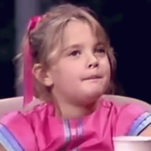 a little girl in a pink dress is sitting in a chair with a cup of coffee .