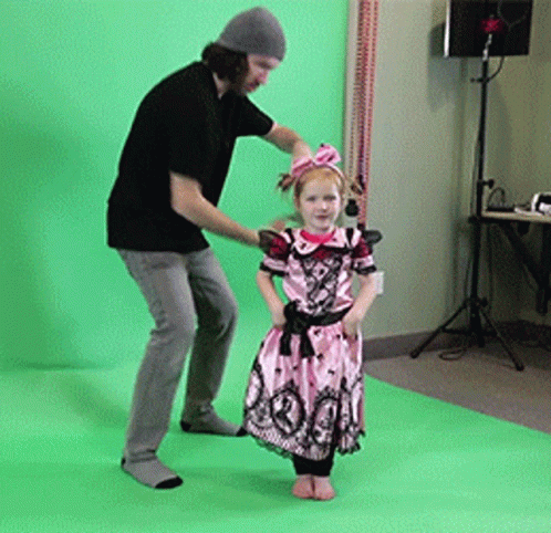 A Little Girl In A Pink Dress Is Standing Next To A Man GIF