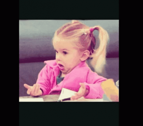 A Little Girl In A Pink Jacket Sitting At A Table GIF