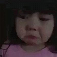 A Little Girl In A Pink Shirt Is Crying And Making A Sad Face . GIF