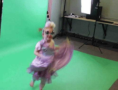 A Little Girl In A Purple Dress Is Dancing In Front Of A Green Background GIF