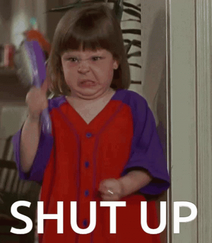 A Little Girl In A Red And Purple Shirt Is Holding A Brush And Making A Face With The Words Shut Up Behind Her GIF