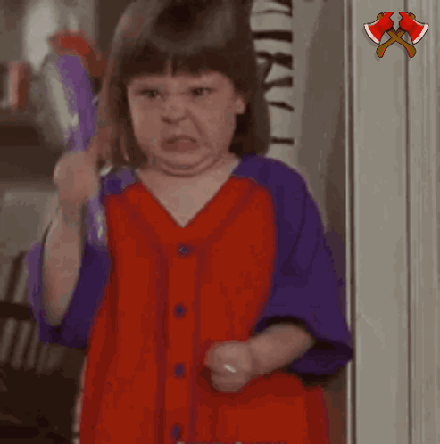 A Little Girl In A Red And Purple Shirt Is Holding A Purple Object And Saying Hushh GIF