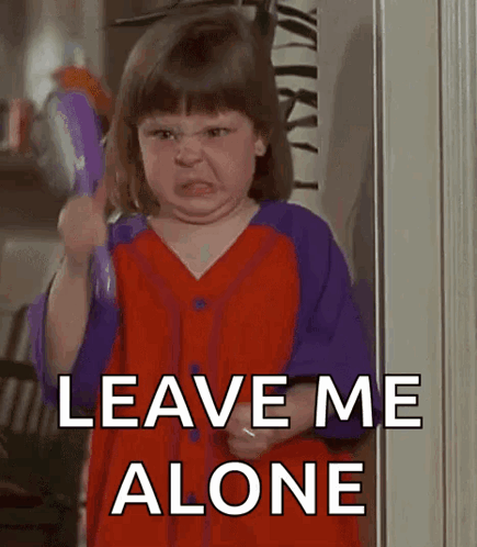 a little girl in a red and purple shirt is holding a toy and saying leave me alone .