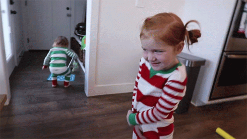 A Little Girl In A Red And White Striped Pajama Stands Next To A Toddler In A Green And White Striped Pajama GIF