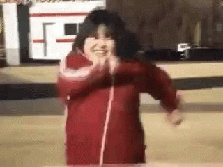 A Little Girl In A Red Jacket Is Dancing In Front Of A Camera . GIF