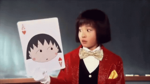 A Little Girl In A Red Suit And Bow Tie Is Holding A Playing Card With A Cartoon Character On It . GIF