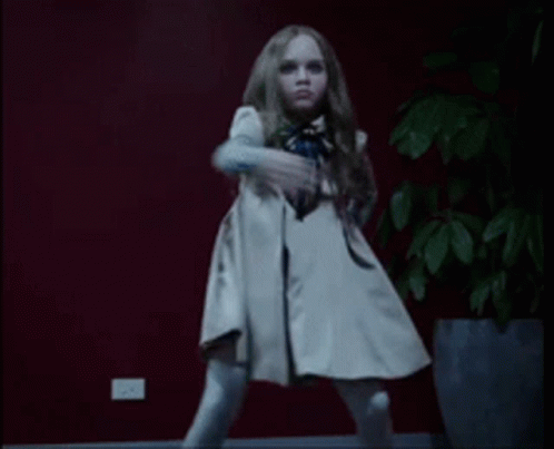 A Little Girl In A White Dress Is Dancing In Front Of A Potted Plant GIF