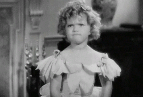 A Little Girl In A White Dress Is Making A Funny Face . GIF
