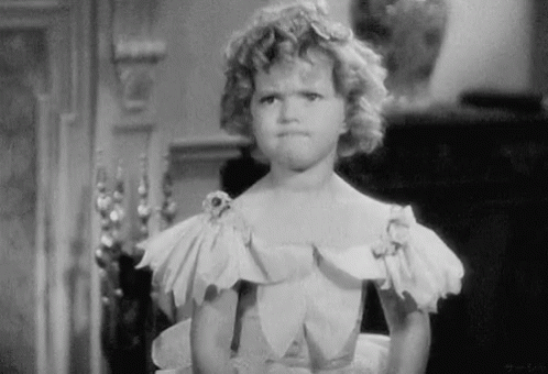 A Little Girl In A White Dress Is Making A Funny Face GIF
