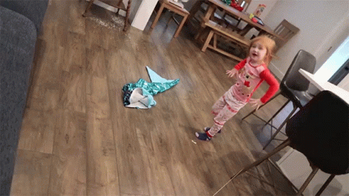 A Little Girl In Pajamas Standing On A Wood Floor GIF