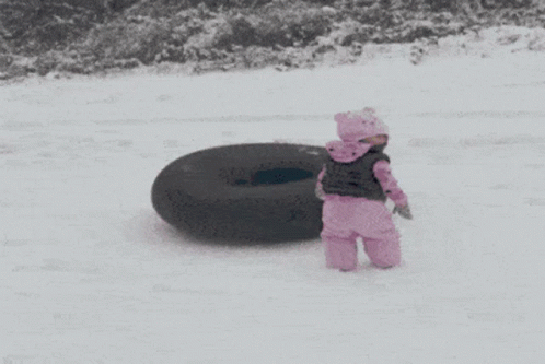 A Little Girl In Pink Standing Next To A Black Tire GIF