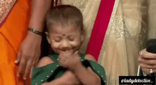 A Little Girl Is Being Held By A Woman And Making A Funny Face . GIF