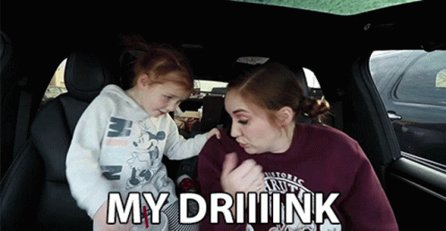 A Little Girl Is Being Held By A Woman In A Car And The Words My Driiink Are Above Them GIF