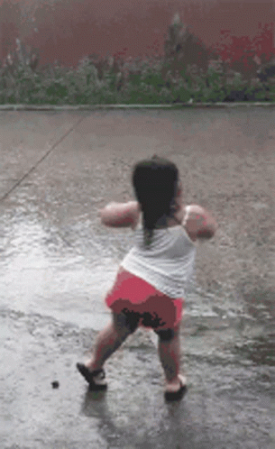 A Little Girl Is Dancing In A Puddle Of Water GIF