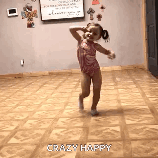 A Little Girl Is Dancing In A Room With A Wooden Floor . GIF
