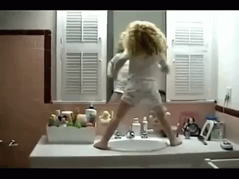 A Little Girl Is Dancing In Front Of A Bathroom Sink GIF