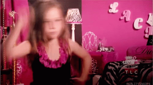 A Little Girl Is Dancing In Front Of A Pink Wall With The Word Tlc On It GIF