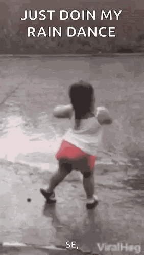 A Little Girl Is Dancing In The Rain On A Wet Sidewalk . GIF