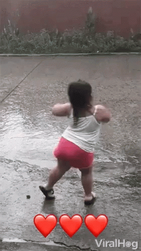 A Little Girl Is Dancing In The Rain With Three Red Hearts . GIF