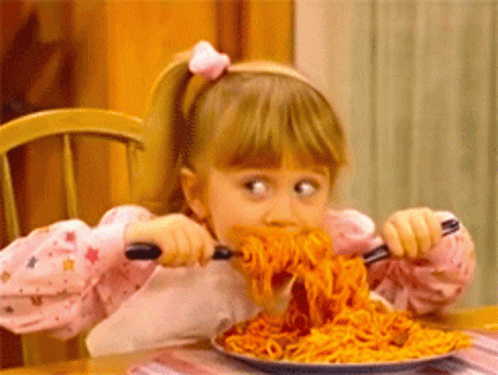 A Little Girl Is Eating Spaghetti With A Fork And Spoon . GIF