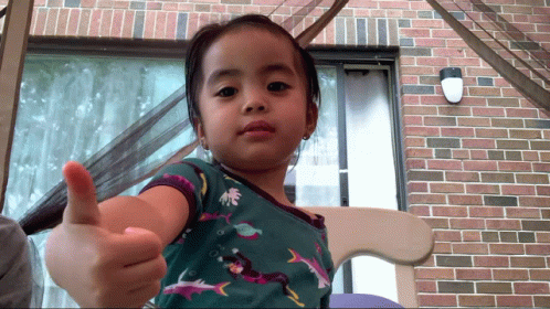 A Little Girl Is Giving A Thumbs Up Sign GIF