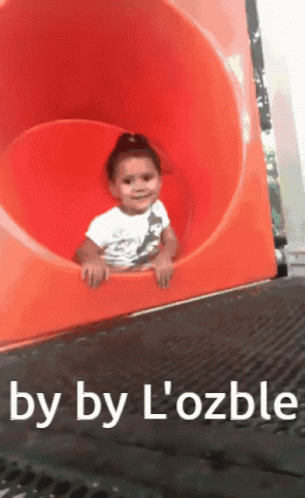 A Little Girl Is Going Down An Orange Slide With The Words By By L' Ozble Below Her GIF