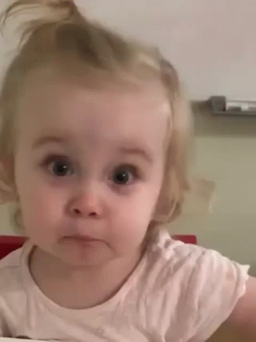 a little girl is making a funny face while looking at the camera .