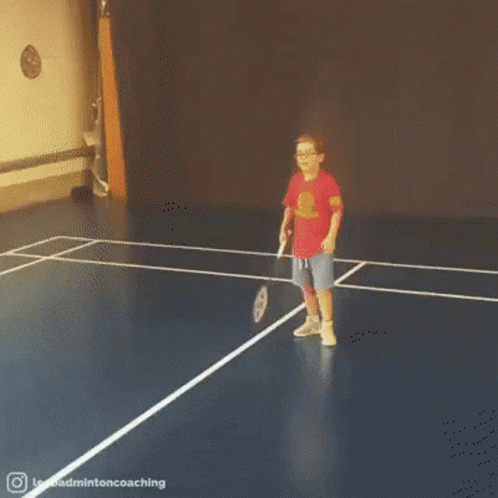A Little Girl Is Playing Badminton On A Blue Court . GIF