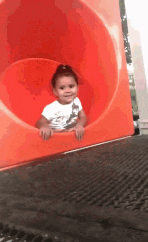 A Little Girl Is Playing On A Red Slide GIF